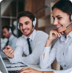 Atendentes de call center sorrindo e usando headsets enquanto trabalham em laptops.