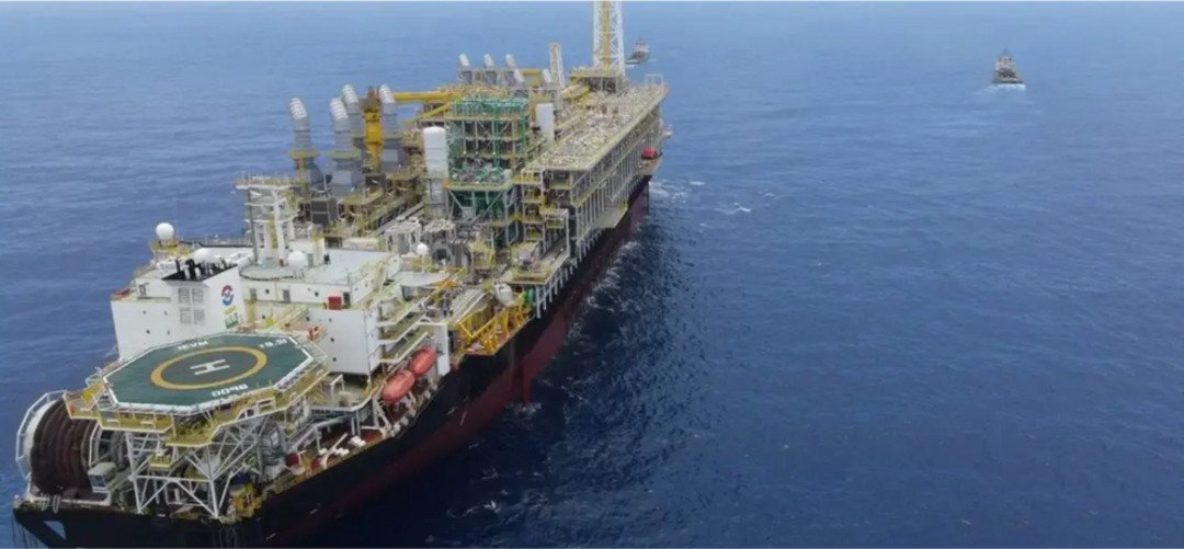 Plataforma de petróleo no mar, usada para exploração e produção offshore, com amplo maquinário e heliponto visíveis.