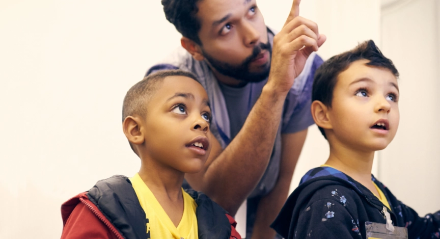 Crianças e professor apontando.