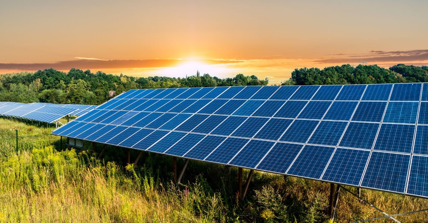 Painéis solares em campo verde sob o pôr do sol, simbolizando energia limpa e sustentável